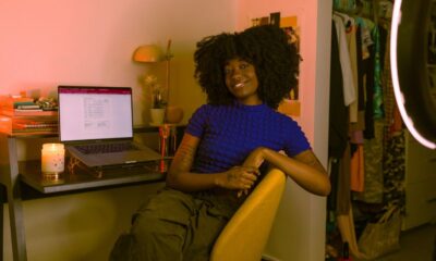 Black female content creator smiling at the camera sitting in a room with her laptop and light ring